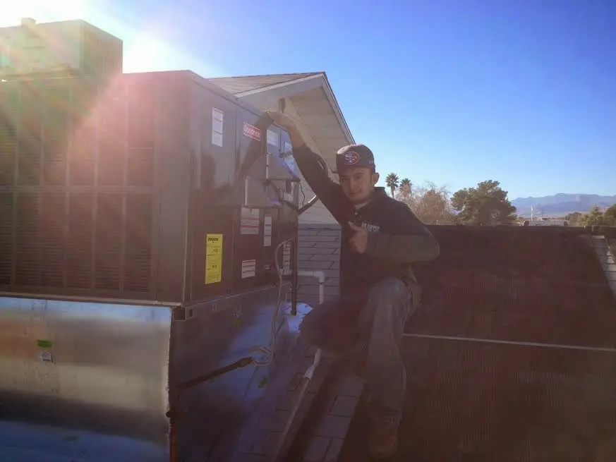 HVAC technician performing AC Tune-Up on a rooftop unit in Wilton